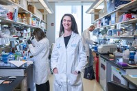 Dr. Mara Sherman in her lab, with two trainees working in the background